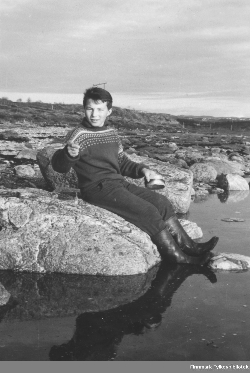 Torbjørn Nymo fotografert sittende i fjæra i Brennelv mens han fisker med en kasteboks.