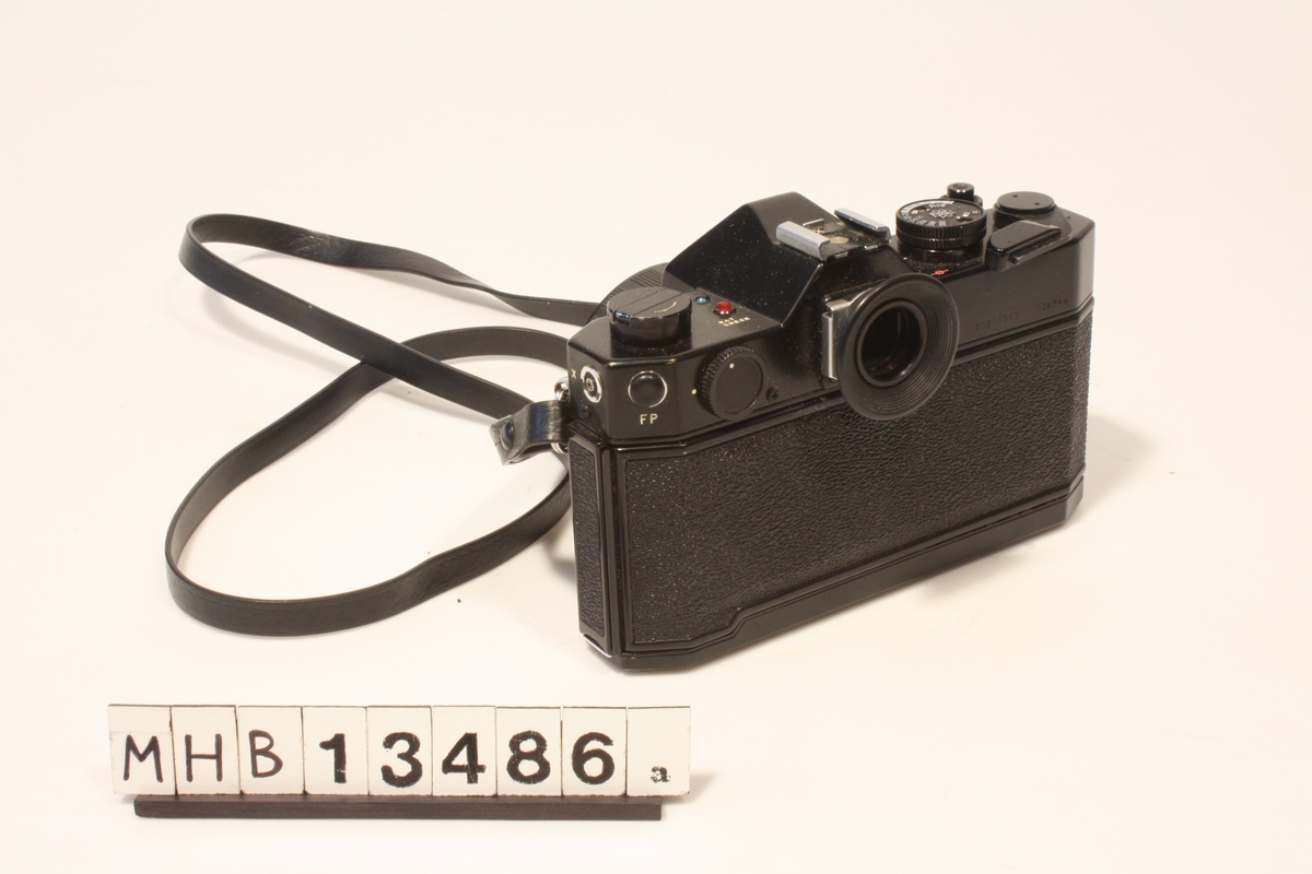 Speilreflekskamera for 135-formatet påmontert 50 mm objektiv og skulderreim.