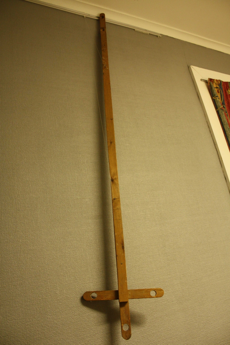 Langt, utrekkbart stag, formet som et kors i endene hvor det er boret tre gjennomgående hull for stearinlys.