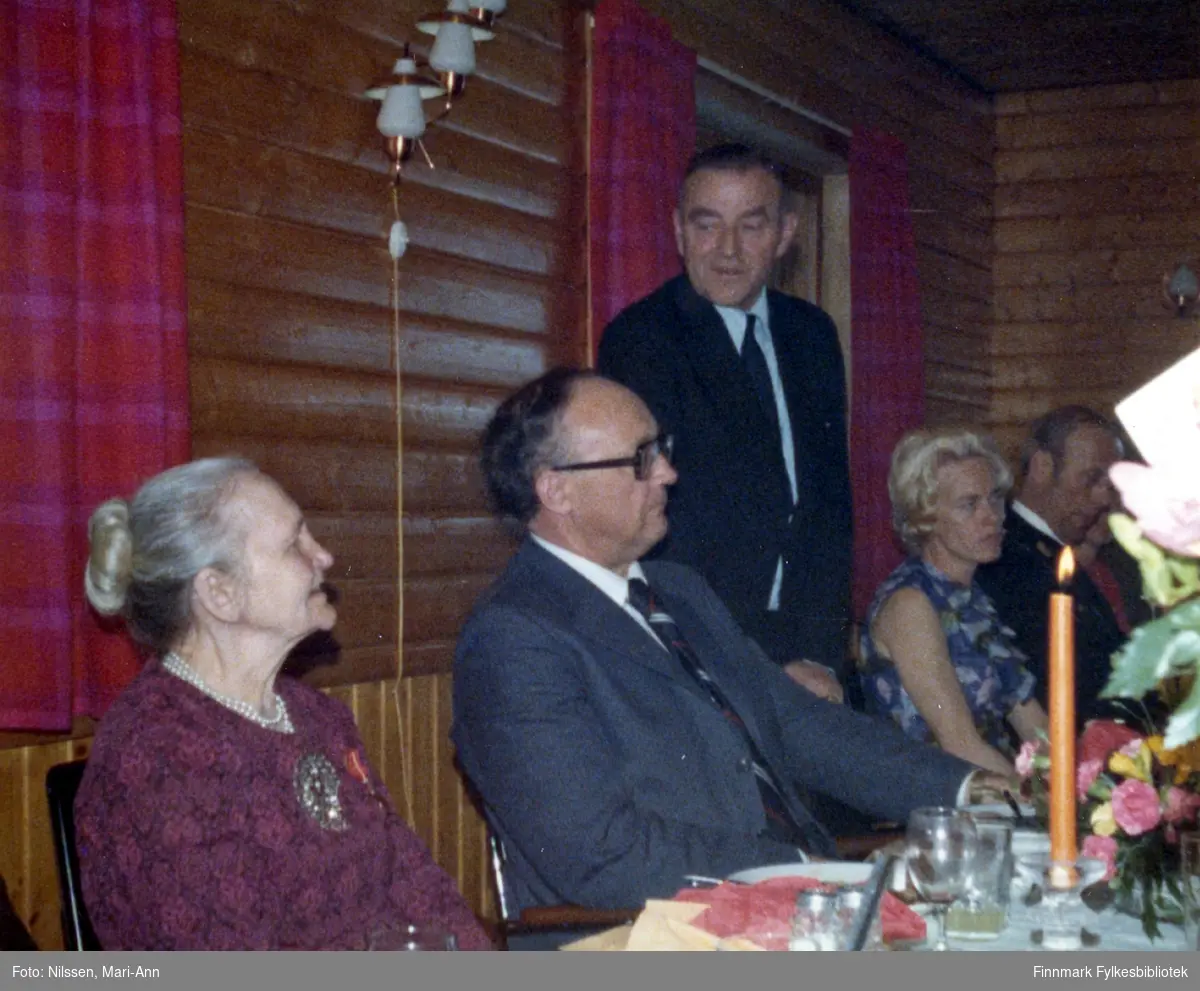 Marie Sivertsen ble tildelt Kongens fortjenestemedalje i gull under en høytidelig tilstelning på Neiden fjellstue, 3. mai 1977. På dette bildet taler ordfører Arnt Isaksen. Fylkesmann Anders Aune til venstre for ordfører Arnt Isaksen.