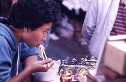 Mann spiser nudler på gaten i Hong Kong.