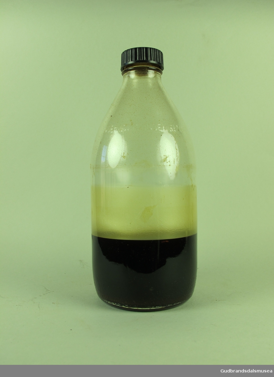 Blank rund glassflaske med sort plast kork.
Inneholder ca 1/3 med størknet veske.