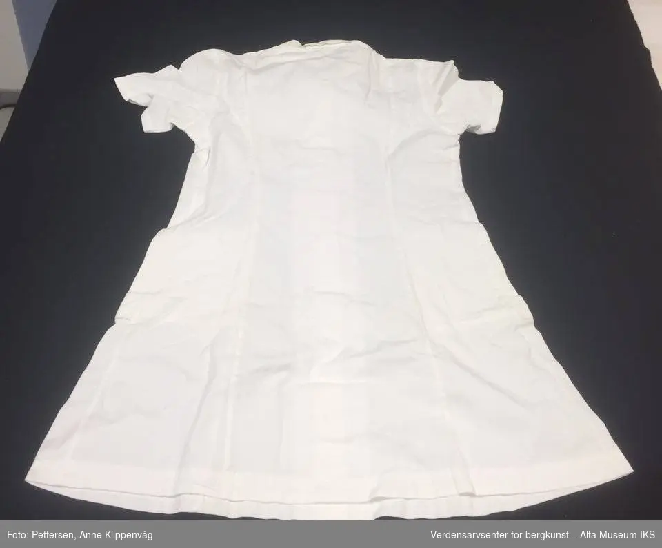 Hvit kortermet sykepleieruniform med seks hvite knapper i plast, og krage.