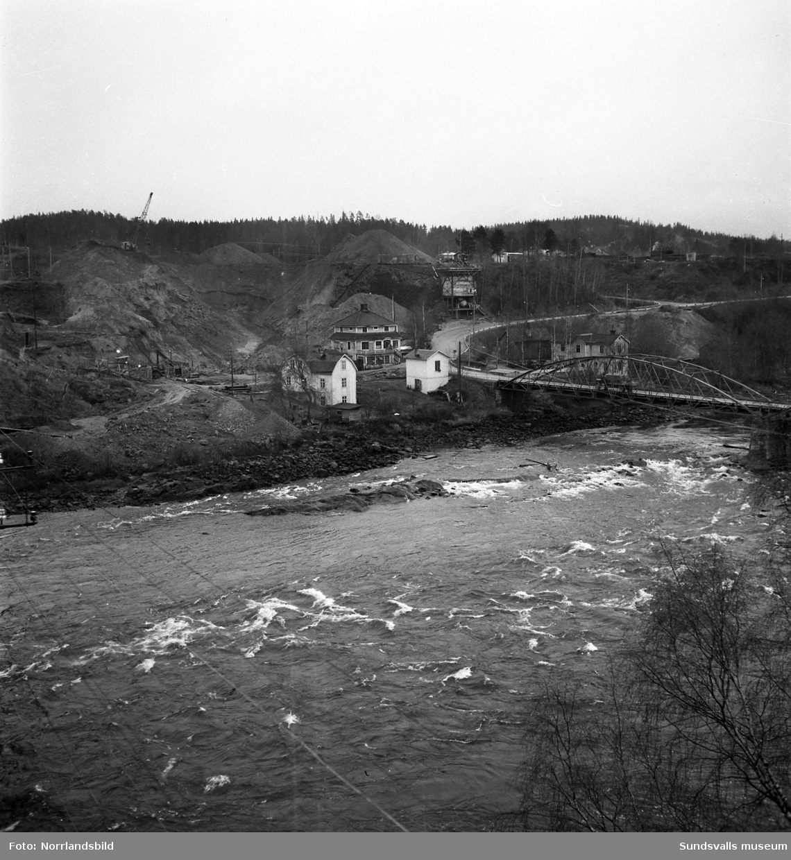 I Bergeforsen har grävningsarbetena inför bygget av kraftverket börjat. På bilderna syns järnvägsbron, gamla landsvägsbron samt byggnader på områden som numera är uppdämda.