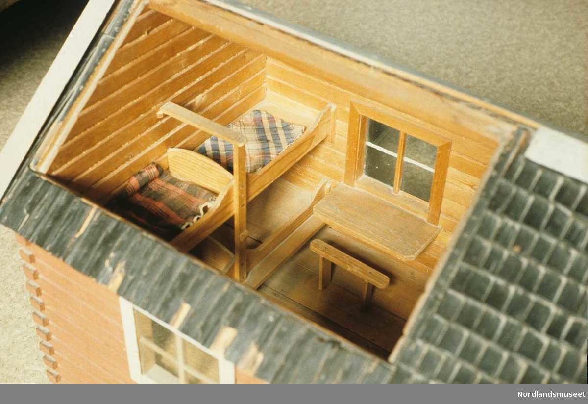 Utstilling på Nordlandsmuseet. Modell av rorbu. Deler av taket med åpning som viser noe av selve innredningen inne i bygningen.