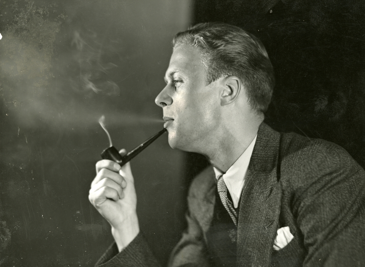Portrett av mann i dress som røyker pipe.