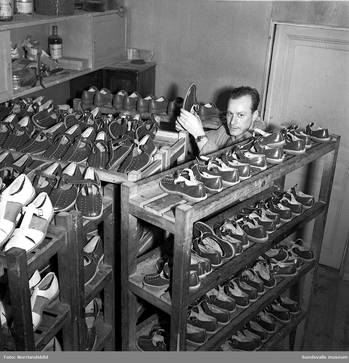 Heffners skofabrik. Trots att snön yrde utanför fönstret producerades det sandaler och fritidsskor för högtryck vid Industribolagets skofabrik i Heffners en februaridag 1951. Närmare bestämt 250 par om dagen färdigställdes och en av de fingerfärdiga nåtlerskorna på företaget var fru Svea Haglund som här med säker hand är sysselsatt med att förse sandalerna med bakkappor. Med tio år i branschen kunde hon det mesta av hantverket. Av fabrikens tjugotalet anställda var det sju kvinnor, så kallade nåtlerskor, och årsproduktionen låg på mellan 20.000 och 25.000 par skor.
