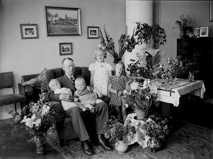 Rumsinteriör, en man och fyra småbarn.
A. Ekvall på 70 årsdagen.