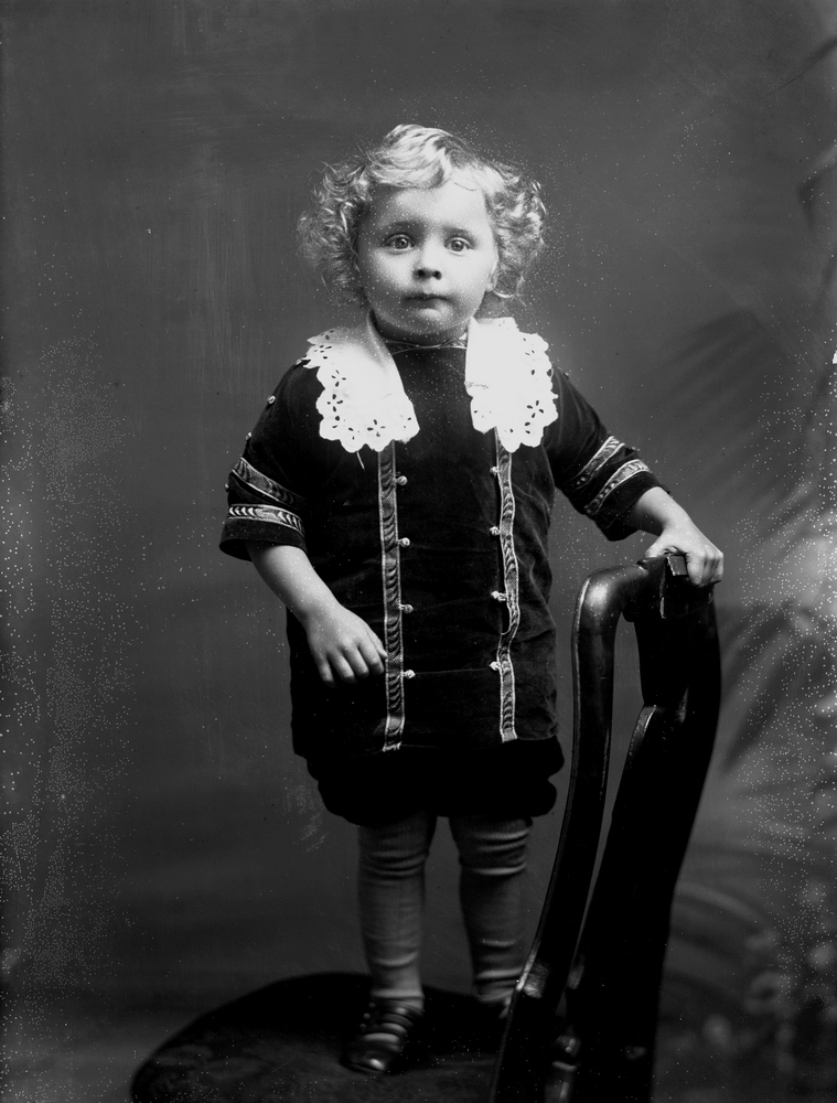 En liten pojke på en stol. Helge Hallberg, född 1911-12-10 vid Svennevadsby i Svennevad, död 1953-12-27 vid St. Görans sjukhus i Stockholm.
Stolen är från Skogaholms herrgård. Ägs nu (år 2016) av Erik Hallberg i Stockholm.
