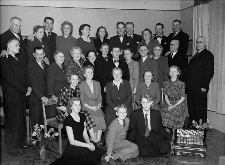 Rumsinteriör, gruppbild. 
Fotografiet föreställer fru Anna Larsson (född Nors). Troligen taget vid hennes 70 års dag 14 januari 1951.
