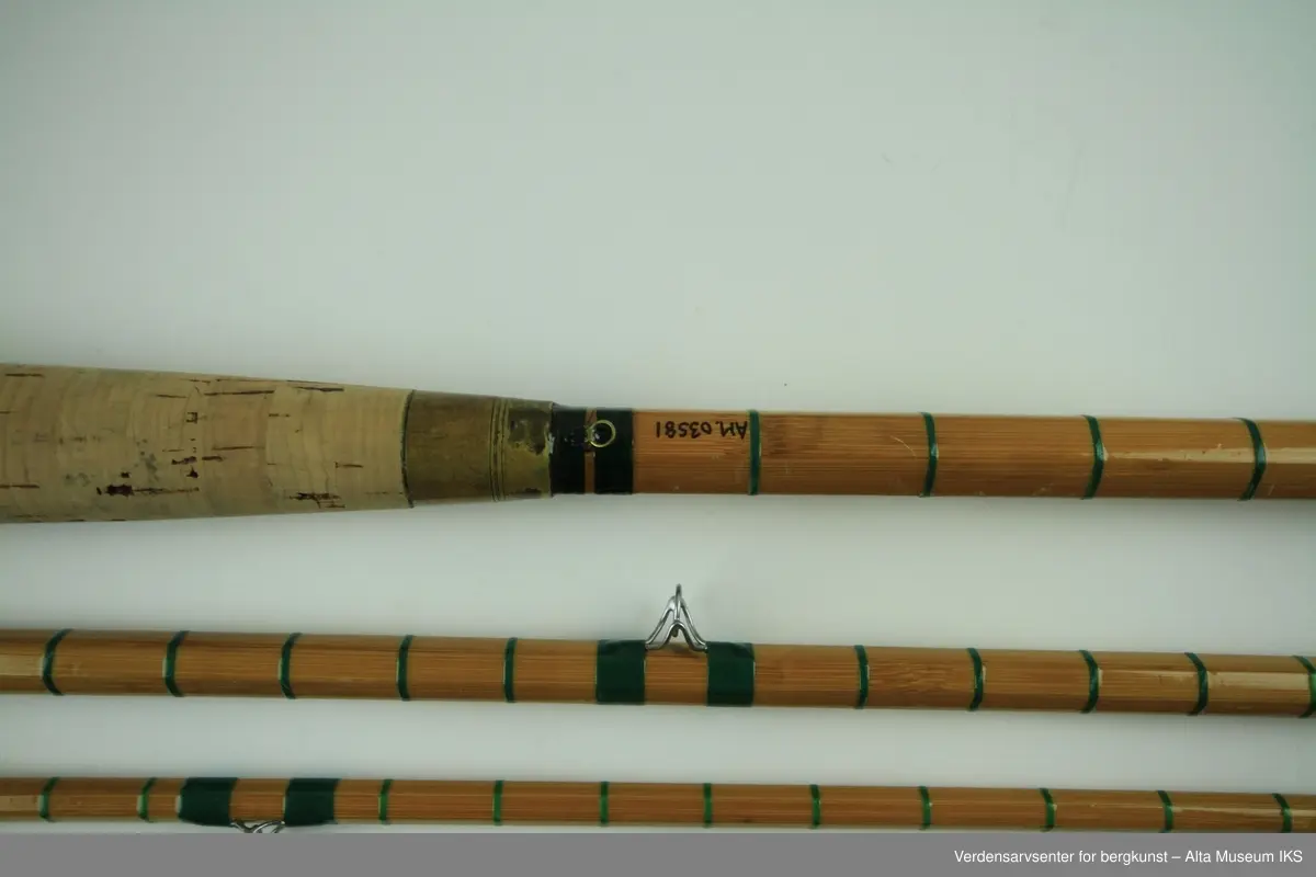 Tohånds fluestang. Tredelt. Tungbygd splitcane med stålkjerne. klasse # 11-12. Skruholker (kom etter knyteholkene) av messing. Sliding ring snellefeste. Har vært brukket i toppen mellom andre og tredje ring. Nye grønne surringer. Endebutt i messing og gummi.