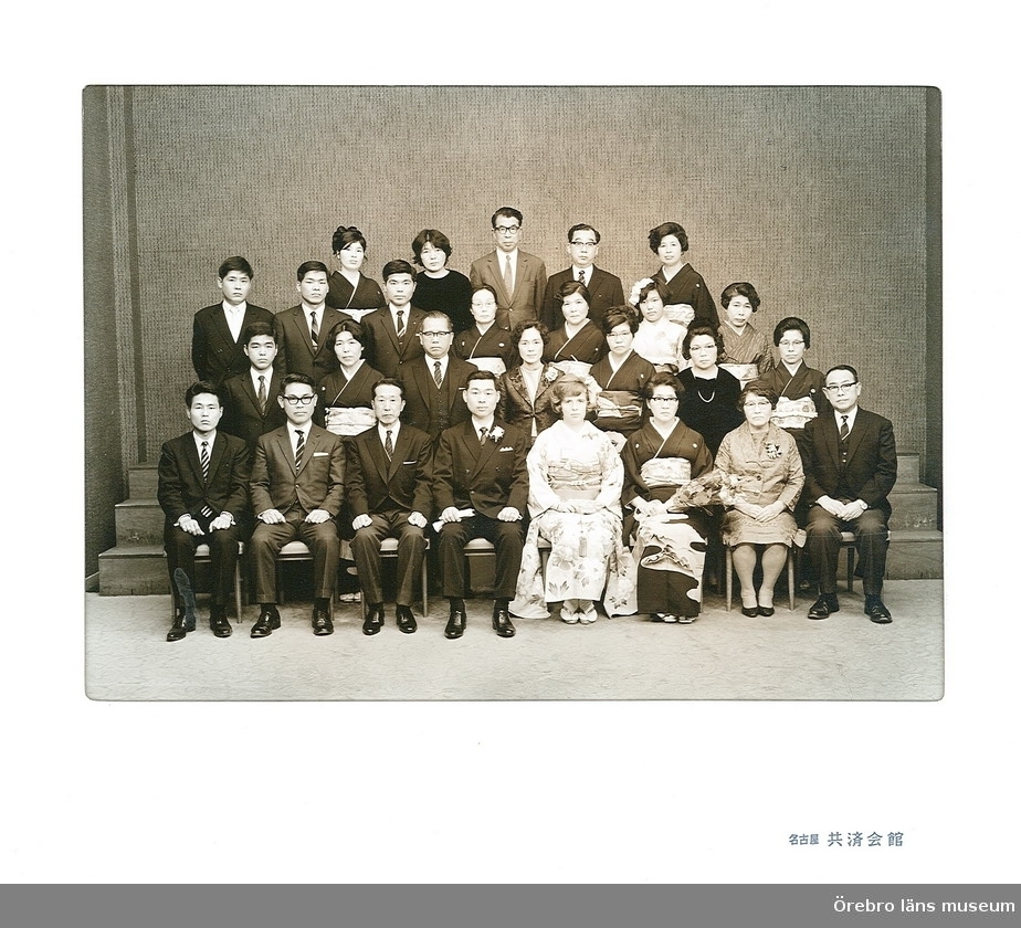 Bröllopsbild.
Samlingsbild från bröllopet i Japan. På bilden ses Akira Matsubaras anhöriga. Han själv och Carine klädd i kimono sitter i mitten på första raden. 
Originalbilden är tagen i samband med bröllopet 20 mars 1969, av en professionell fotograf i en speciell kommunal hall i staden Nagoya Kyosai Kaikan, Japan.
Bilderna är skannade från Carine (Karin) Matsubaras fotoalbum i samband med dokumentationsprojektet "Brevet til framtiden". Carine Matsubara medverkade i detta projekt med ett långt brev där hon bl.a. berättar hur hon träffade sin make Akira Matsubara och gifte sig med honom. Brevets id-nummer i samlingen är: 54.
Se Dnr: 2004.910.194 för vidare upplysningar om projektet.
