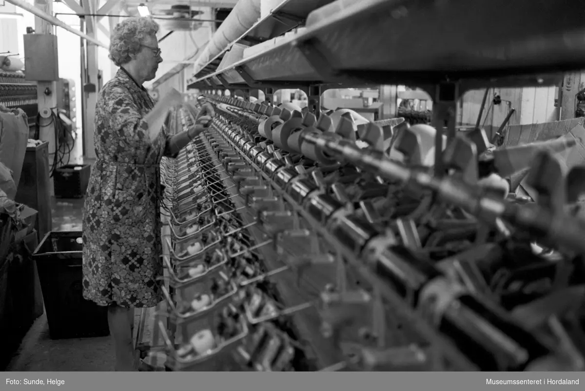 Arbeidsliv ved Salhus Tricotagefabrik i Salhus, Bergen i 1976. Kvinne arbeidar ved spolemaskin i 1910-bygget på Salhus Tricotagefabrik.

T.v: Magda Sellevold