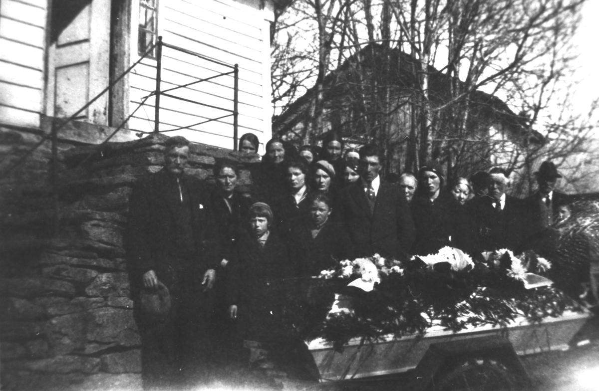 Gruppefotografi av gravfølget ved båra til Karen Ødegård (f. Apalset) under hennes begravelse. Båra ligg på ei vogn med hjul.