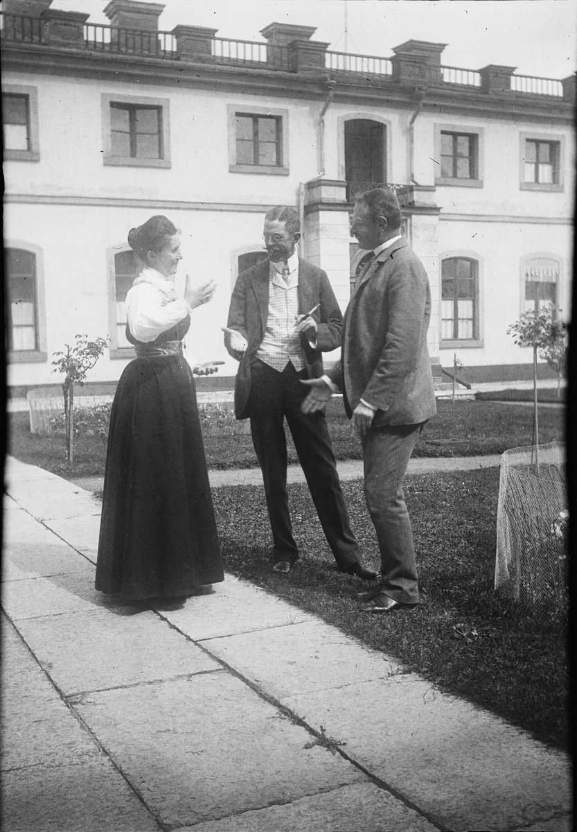 Drottning Victorias bilder. Gustaf V samtalar med en herre och en dam i Tullgarnsdräkt på Tullgarns slott.