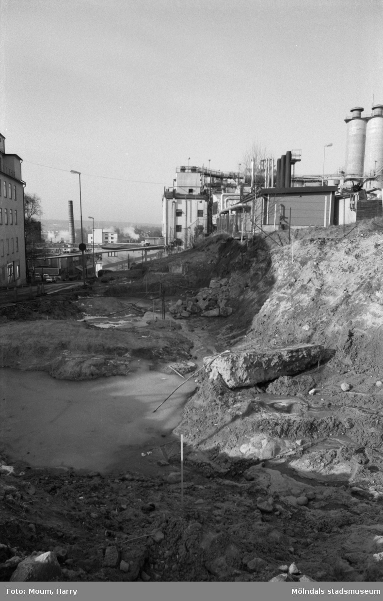 Vägarbete i "Kråkan", Kvarnbygatan i Mölndal, år 1984. Till höger ses fabriksbyggnader tillhörande Soab.

Fotografi taget av Harry Moum, HUM, Mölndals-Posten, vecka 12, år 1984.