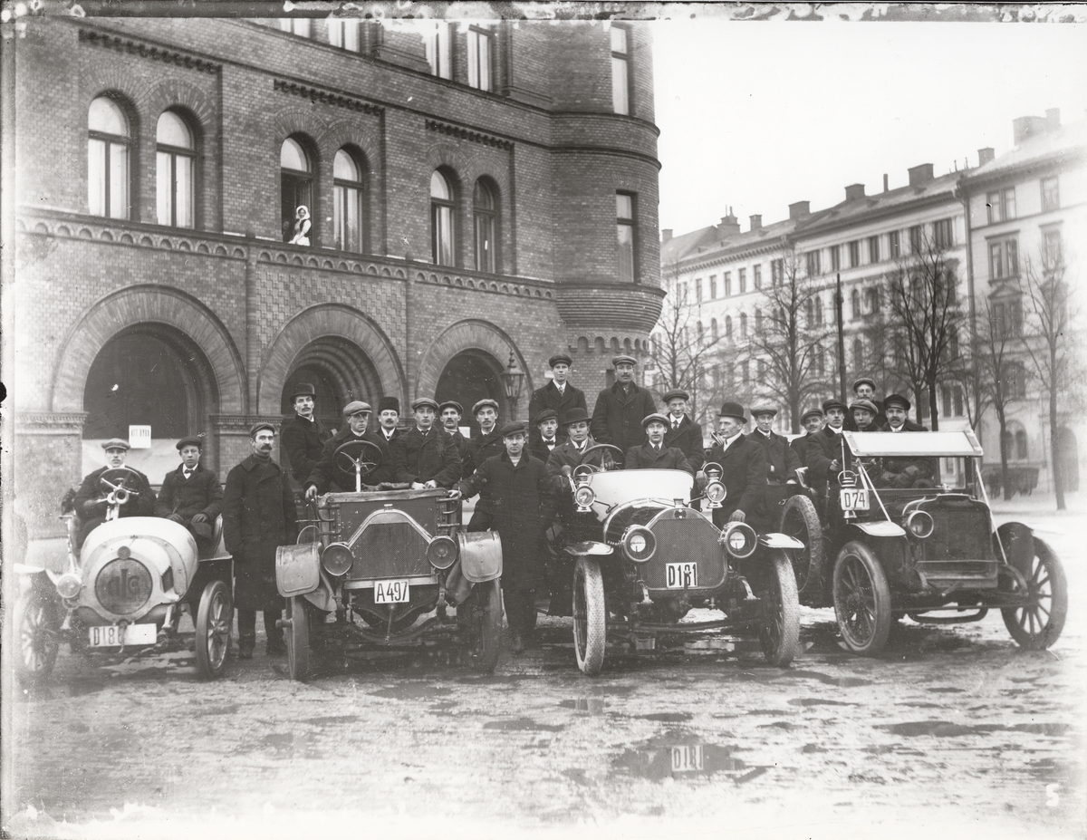 Elever vid Eric Lundviks körskola, samlade kring fyra automobiler framför huset Karlaplan 10, omkring 1915-1920.