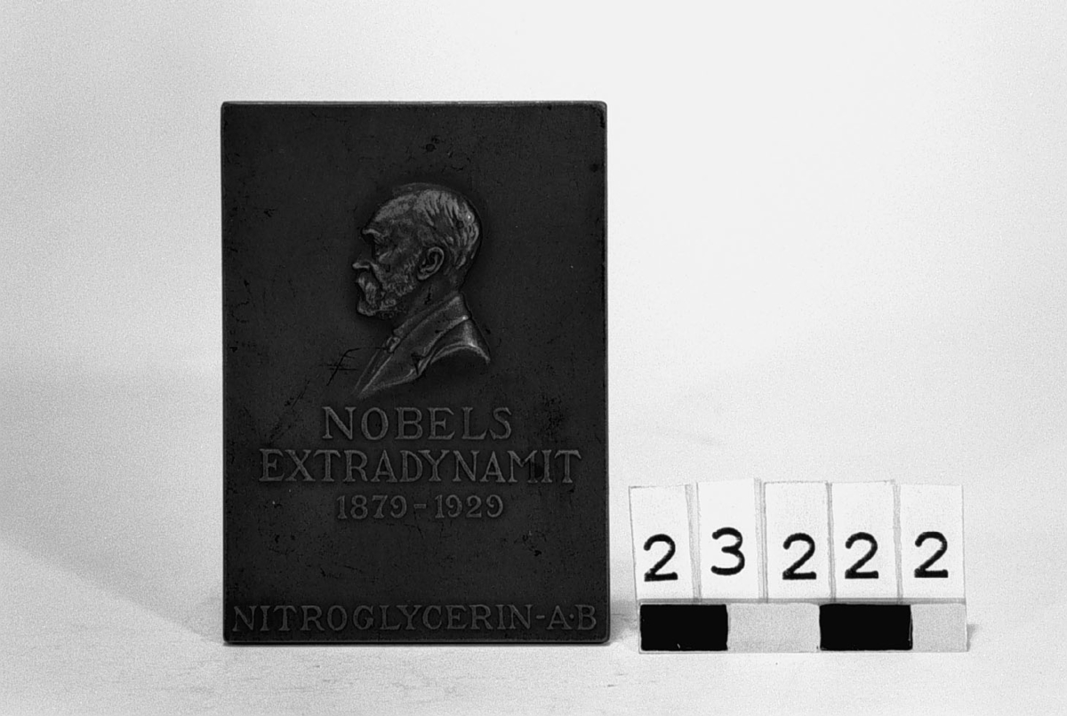 Minnesplakett i brons över Alfred Nobel, utgiven av Nitroglycerin-Aktiebolaget till 50-årsdagen för hans uppfinning av extradynamiten. Porträtt vänster profil, "Nobels extradynamit 1879-1929" "Nitroglycerin-Aktiebolaget".