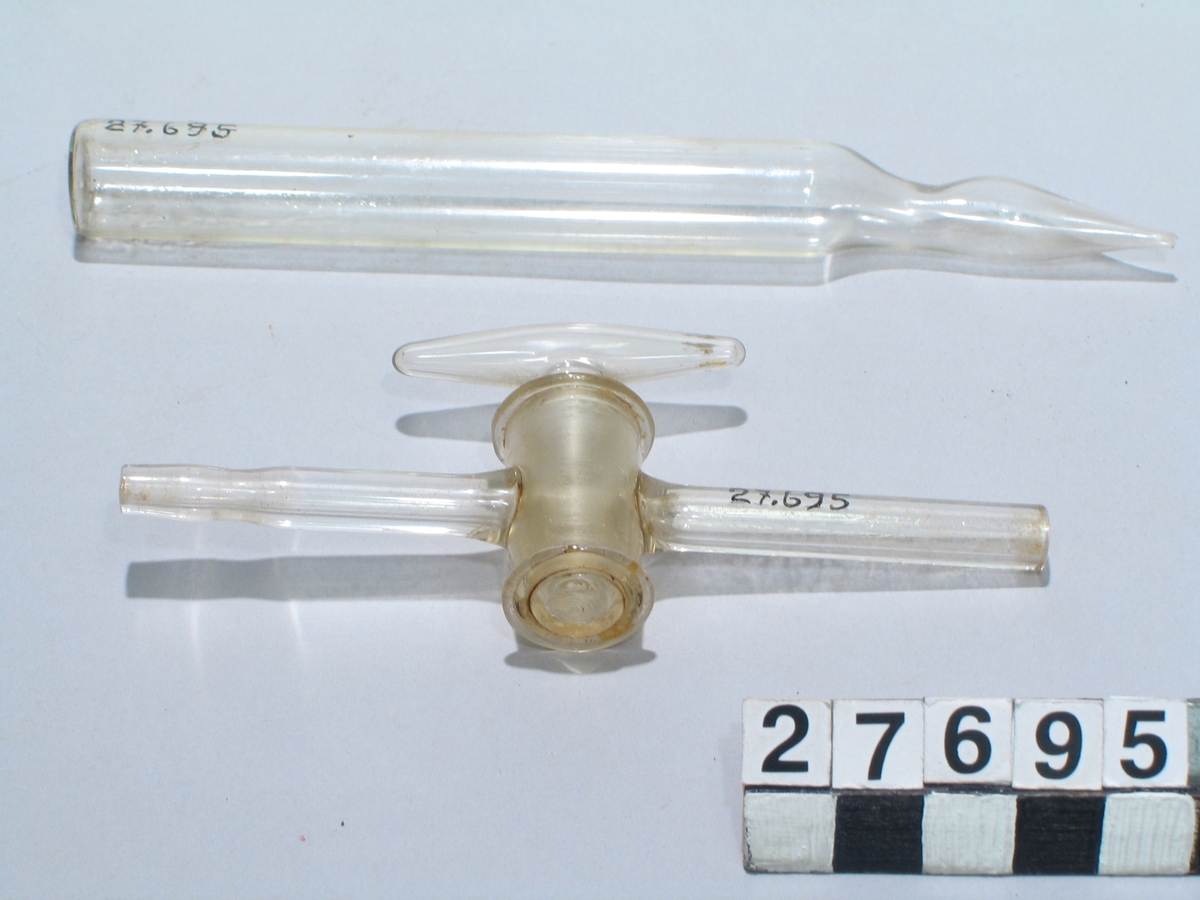 Diverse förmål av glas för kemiska laborationer. Mindre retort med inslipad propp, kran av glas med inslipad propp, mindre pipett, två rör med platt botten, det ena med utdragen öppning.
