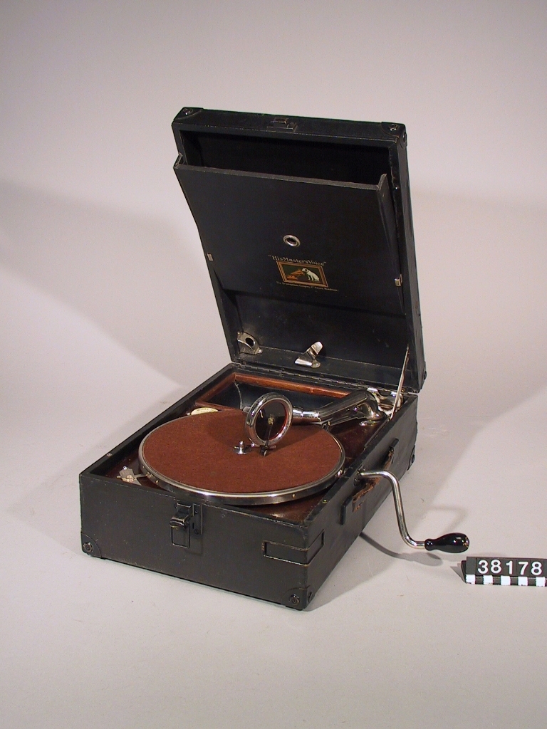 Resegrammofon med fjäderverk och vev, i låda klädd med svart konstläder. 25 cm skivtallrik. Hastighet 78 v/min. Ljuddosa HMV 4