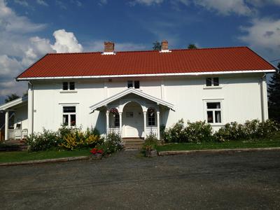 Sagstua skolemuseum og Sigurd Hoels hjem. Et hvitt hus med blomster langs veggene. To etasjer.