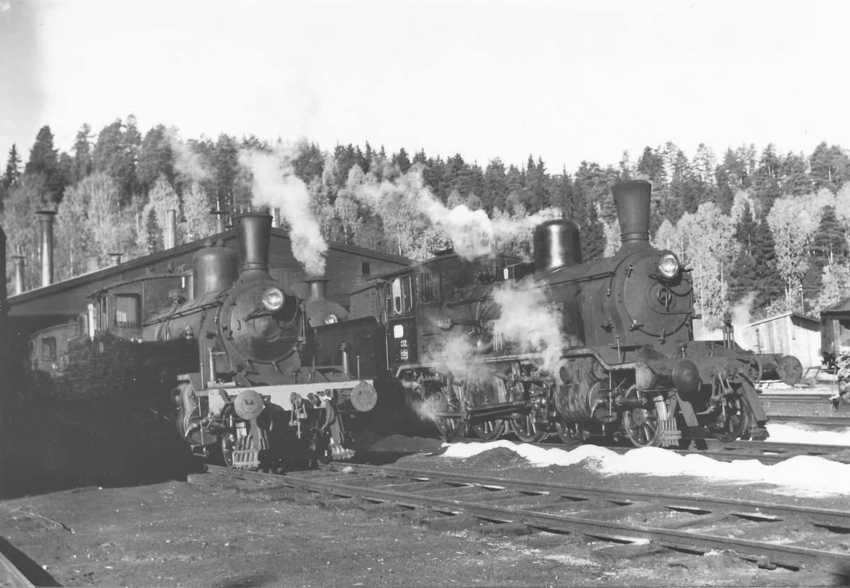 Damplokomotiver utenfor lokstallen på Hønefoss. Til venstre lok type 21, til høyre lok type 18c 212.
