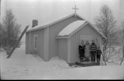 Nuvvus kapell i Utsjok kommune i Finland. Fire personer står