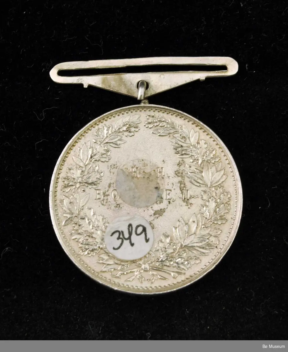 Sirkelformet medalje med feste for bånd