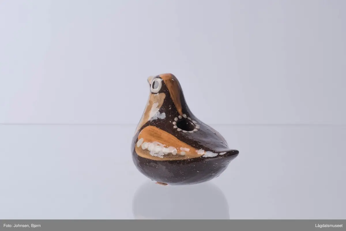 Det er ingen spesifikke motiv på gjenstanden, men utformelsen er en fugl. Motivene ellers består av ornamenter som danner blant annet vinger.