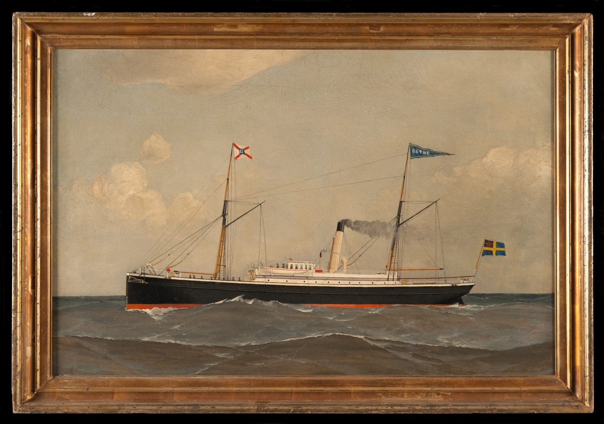 Ångfartyget GÖTHE till sjöss, visande babords sida, svartmålat med vit överbyggnad samt skonertriggat. Bolagsflagg på förtoppen, namnvimpel på stortoppen och svensk flagg med unionsmärke akter ut.