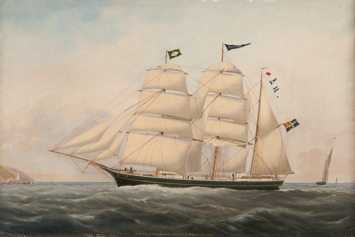 Tremastade barkskeppet MARY ANN av Sundsvall (1877), seglande för styrbords halsar, visande babords sida. Grönmålat skrov med gul list, vitmålad inombords. Unionsflagga på gaffeln. Neptuniordens flagga på fockmasten. T.v. kustparti, t.h, en jakt.
Stävornament.