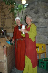 To damer i middelalderkjole som serverer i Ølstua