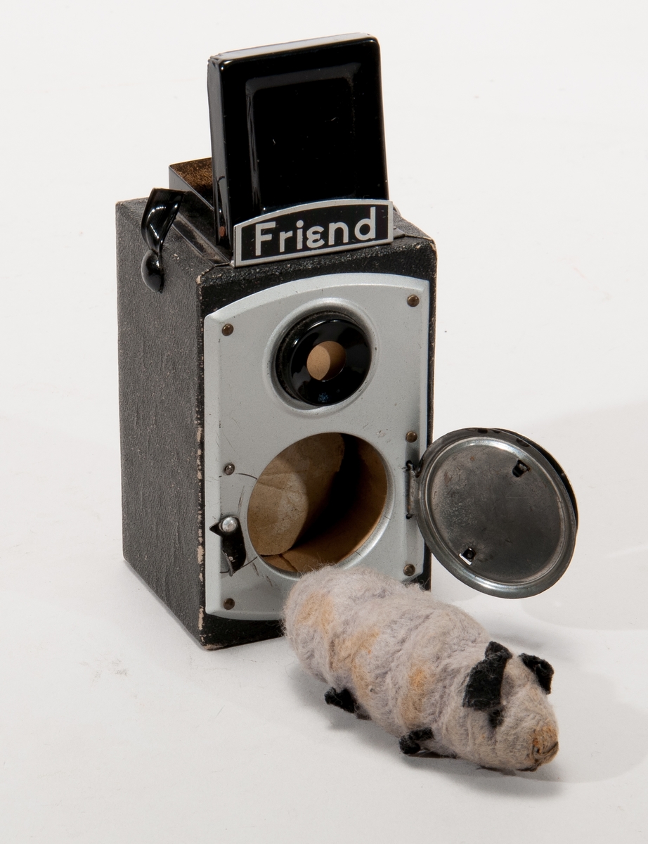 Leksakskamera (skämtartikel) med "råtta" (tygomsluten fjäder) som hoppar ut när man tar en bild. Kameran märkt: "Friend" samt "Wonder Camera".
I originalförpackning.