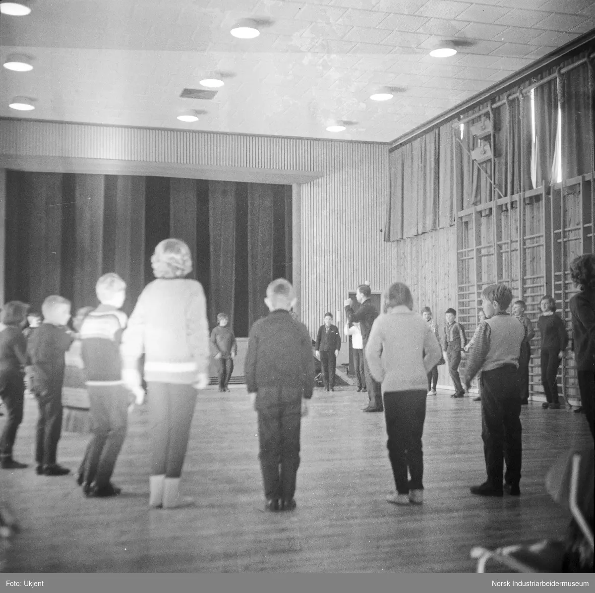 Barn i gymsal på Atrå skole. Barn stående i sirkel foran ribbevegg.