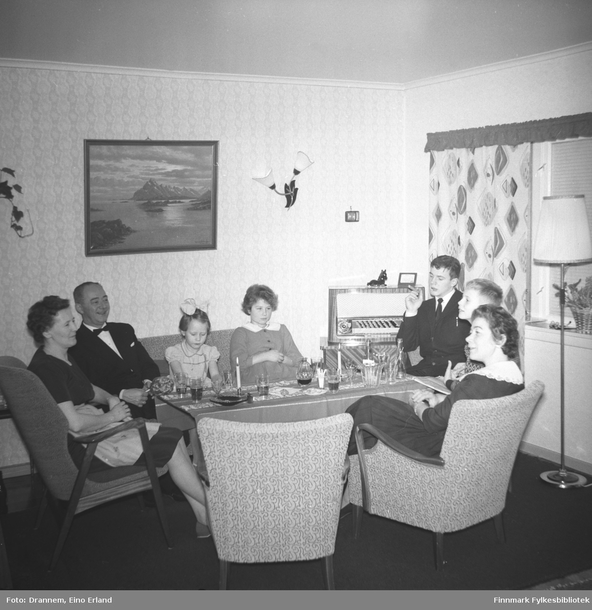 Pentkledte mennesker i selskap hjemme hos familien Sørensen i Hammerfest. Antagelig er det Turid Karikoski som sitter som nr. 4 fra venstre og Jenny Drannem helt ytterst til høyre på bildet.
