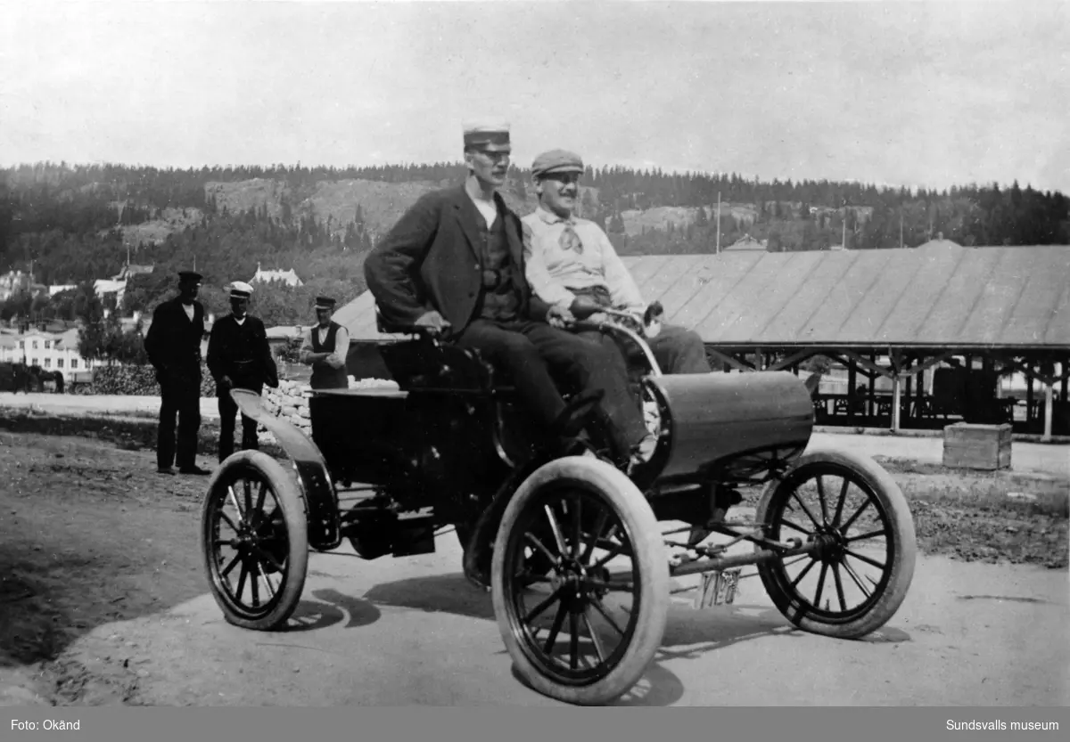 Direktör Zadig Hirschfeldt med Sundsvalls första automobil, en Oldsmobile Curved Dash som användes för affärsresor i karamellfabrikens tjänst ända upp till Haparanda. Chaufför var Herman Höglund (närmast kameran) sedermera föreståndare för Norrköpingslithografens tryckeri i Sundsvall.