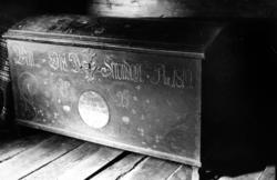 Kiste med påført rankemaling med rosetter o.l imellom. Inskr