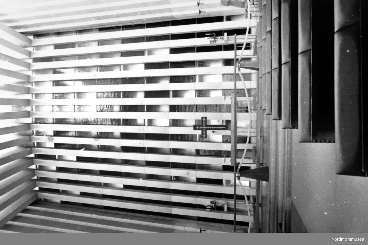 bildet skal stå!
Kirkelandet Kirke (arkitekt Odd  Kjeld Østbye) i Roligheten på Kirkelandet i Kristiansund. Interiørbilde som viser alteret og Gunnar S Gundersens glass-mosaikkvegg i bakgrunnen. 
Den siste gudstjenesten for Kirken på Lyhshaugen ble holdt søndag 21. april 1940. Det ble da holdt høymesse ved stiftskapellan J. S. Garpestad og aftensang ved tredjeprest H. G. Seim. Mandag 29. april gikk flyalarmen, og ved 11:30 tiden ble det kastet store mengder spreng- og brannbomber i området ved kirken, og om ettermiddagen brant kirken ned til grunnen. 

Etter krigen i 1945 tok de kommunen opp spørsmålet om gjenreisning av kirken. Spørsmålet som ble reist først var plassering av kirken, og 2. november ble dette forelagt menigheten. Dette skulle vise seg at å bli vanskeligere enn antatt. Flere forslag ble presentert, som Barmannhaugen og gamle fengselstomta, men ingen av disse forslagene ble godt mottatt i menighetsrådet. Over de neste årene med flere diskusjonsrunder, ble det tilslutt under formannskapets møte den 29. oktober 1955 vedtatt å anbefale at kirken plasseres i Roligheten etter bygningssjefens utarbeidede alternativ 2-55.

Problemet lå nå i at kommunen ikke var eier av Roligheten. Også dette første til forsinkelser da kjøpet havnet i rettssystemet, og ble ikke løst før 26. september 1957 da høyesterett nektet å ta saken inn til behandling. Likevel, arbeidet med reguleringsplanen pågikk hele tiden, og denne ble vedtatt av bystyret den 2. juni 1956, stadfestet 1. august samme år, og fulgt opp ved Kgl. res. av 18. oktober 1957. 

Formannskapet hadde da gitt eierne tilbud om å kjøpe tomten, og med Kristiansund skjønnskommisjon som fastsetter av voldgiftsrett-prisen, ble tomtekjøpet gjennomført. Første gang i 28. oktober 1958 da kommunen kjøpte 5500 m2 eiendom til kr. 99.000, og andre gang med kjøp av tilleggsjord 15. desember 1961 til en verdi av kr. 51.000. Totalt kr. 150.000.

Allerede da var en plankomite blitt satt ned for å se på planløsningen av den fremtidige kirken. Plankomiteen møttes 4. juli 1956, og forslaget ble deretter lagt frem for formannskapet den 20. september 1956. Følgende romprogram ble godkjent og stemt gjennom: forhall, kor, Sal med 600 sitteplasser, menighetssal til 100-150 personer som kan knyttes sammen med hovedsalen, dåpsrom, sakristi, organist og notearkiv, velferdsrom, kjøkken til menighetssal, orgelgalleri, rom for orgelmaskin, materialrom, samt eventuelt kontorer som et alternativ under anbudskonkuransen.

Etter en påfølgende anbudskonkuranse besluttet Kristiansunds menighetsråd i møte 21. oktober 1958 å innstille arkitekt Odd Østbyes utkast "Bergkrystall i roser" som grunn for bygging av ny kirke, og etter flere runder i Kristiansund bygningsråd godkjent den 25. oktober 1961. Ved kgl. Res. 4. november 1961 ble det gitt løyve til gjenoppføring av Kirkelandets kirke etter planer utarbeidet av Odd Østbye. (Se årbok for Nordmøre Museum 1992, side 6 til 12.)

Prisrammen ble fra arkitekt kr. 2.550.000, men etter anbudsrunder ble de billigste anbudene på oppføring av kirken til sammen kr. 3.023.000, hvorpå byggemester Harry Mathisens anbud på de bygningsmessige arbeider var på kr. 2.357.296, mens de andre anbudene på underarbeid påløp på til sammen kr. 665 704. I tillegg måtte det innhentes pristilbud på orgel, som ble levert av orgelmaker J. H. Jørgensen til en pris av kr. 178.000. Et elektroakustisk klokkeanlegg og klokkespill til kr. 65.000 ble donert av Kristiansunds spareskillingsbank, noe formannskapet vedtok å ta imot med takk.

Grunnsteinen for kirken ble lagt søndag, 10. desember 1961 av