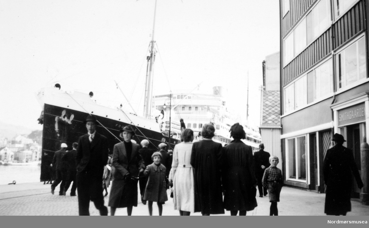 Foucauld x Hoedic, et fransk skip ved storkaia i Kristiansund på 1930-tallet.  Skipet gikk i cruise-fart langs norskekysten i mellomkrigstiden.  Skipet var bygget i 1923.  Navneskifte i 1928.  Foucauld ble satt i brann i et tysk angrep 20. juni 1940.
Passasjerbåt ved Storkaia på Kirkelandet i Kristiansund. Skiltet på bygningen til høyre leses ";Smithgaarden";. Folk spaserer langs kaia i forkant. Bildet er tatt fra Storkaia mot Innlandet. Fra Nordmøre museums fotosamlinger. Reg: EFR
