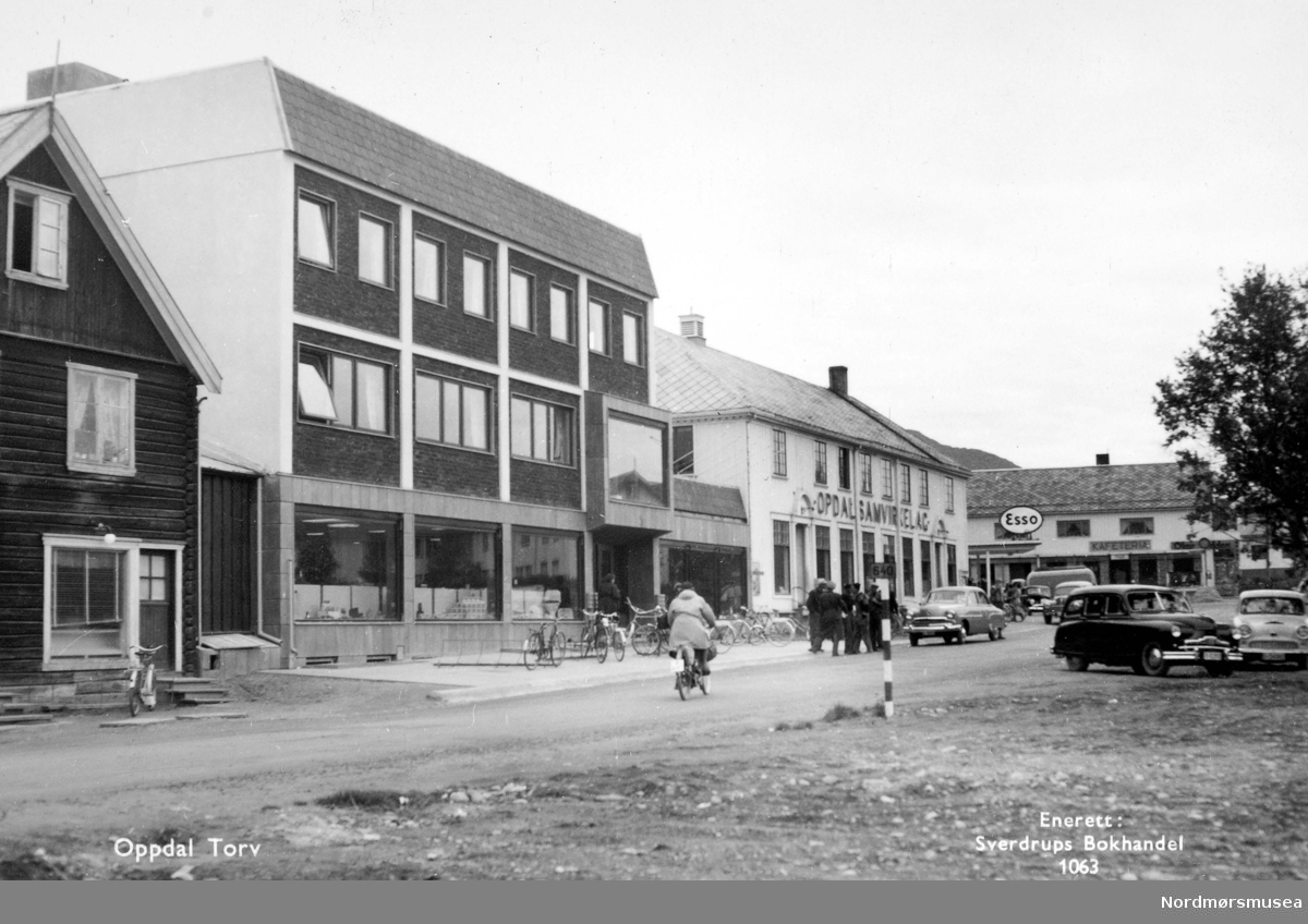 Postkort: 1063 ";Oppdal torv";.  Foto fra  torget i Oppdal kommune, hvor vi ser blandt annet Oppdal samvirkelag, Esso bensinstasjon og en kafeteria. Fra Nordmøre Museums fotosamlinger. Reg: EFR
