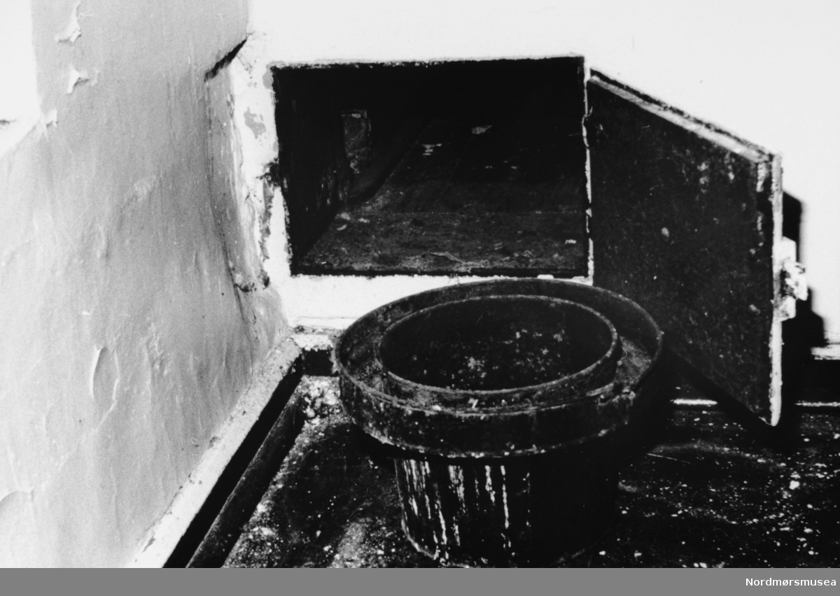 Foto av ei toalettluke med bøtte
fra fengslet i Molde. Datering er ukjent. Serie. se reg. nr. fra KMb-1991-019.0001 til KMb-1991-019.0004. Fra Nordmøre Museums fotosamlinger.
