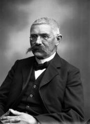 Portrett av en mann med bred bart og briller. Usikkert hvem.