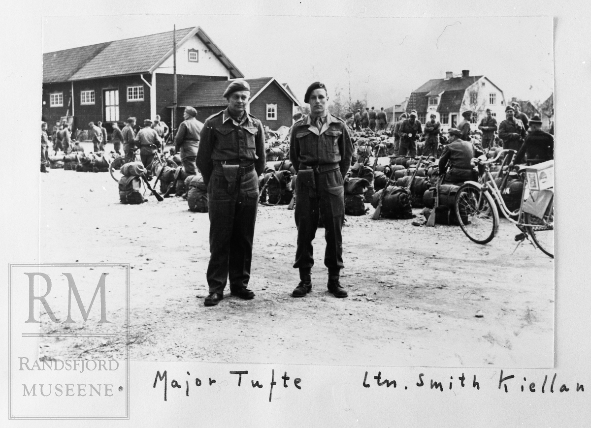 To offiserer foran en gruppe soldater.