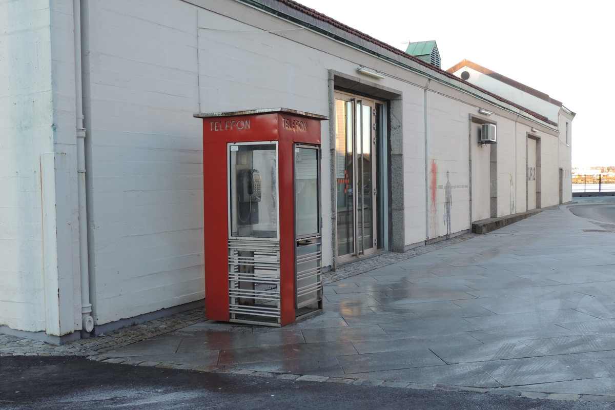 Telefonkiosken står på Strandkaien i Stavanger, og er blant de 100 vernede telefonkioskene i Norge. De røde telefonkioskene ble laget av hovedverkstedet til Telenor (Telegrafverket, Televerket). Målene er så å si uforandret. 
Vi har dessverre ikke hatt kapasitet til å gjøre grundige mål av hver enkelt kiosk som er vernet. 
Blant annet er vekten og høyden på døra endret fra tegningene til hovedverkstedet fra 1933.
Målene fra 1933 var:
Høyde 2500 mm + sokkel på ca 70 mm
Grunnflate 1000x1000 mm.
Vekt 850 kg.
Mange av oss har minner knyttet til den lille røde bygningen. Historien om telefonkiosken er på mange måter historien om oss.  Derfor ble 100 av de røde telefonkioskene rundt om i landet vernet i 1997. Dette er en av dem.