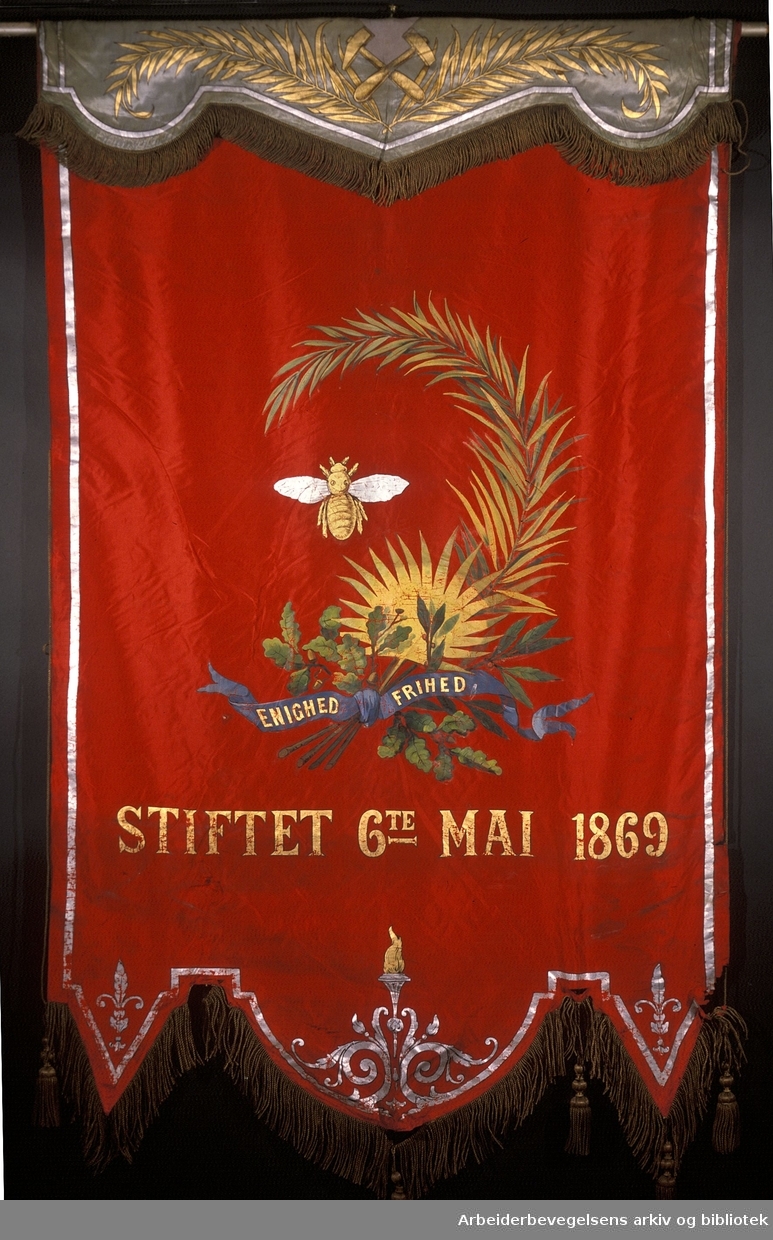 Kongsberg arbeidersamfund.Stiftet 6. mai 1869..Bakside..Fanetekst: Enighed Frihed.Stiftet 6te mai 1869