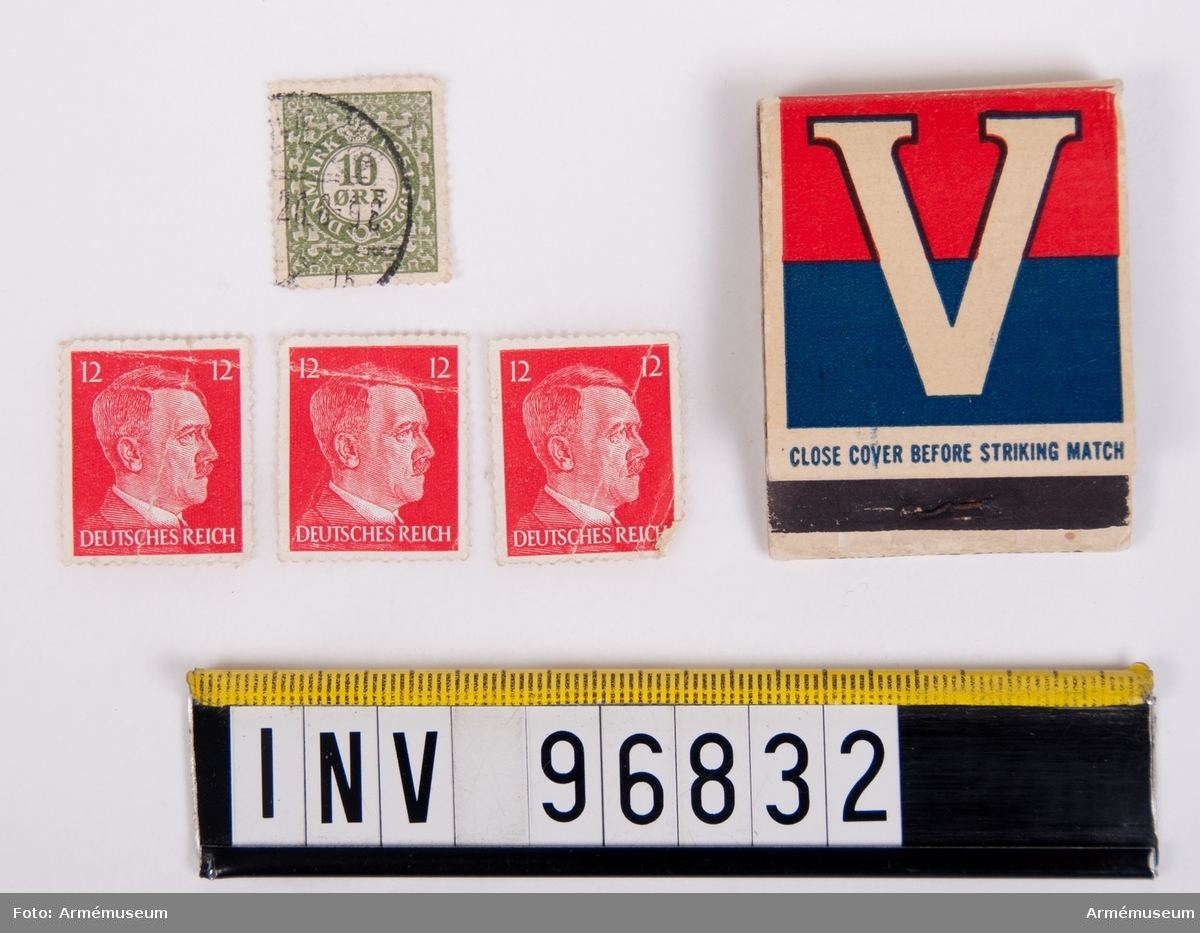 Tändsticksask innehållande tändstickor samt fyra frimärken, varav tre stycken tyska röda föreställande Adolf Hitler och ett grönt danskt med texten 10 ÖRE.