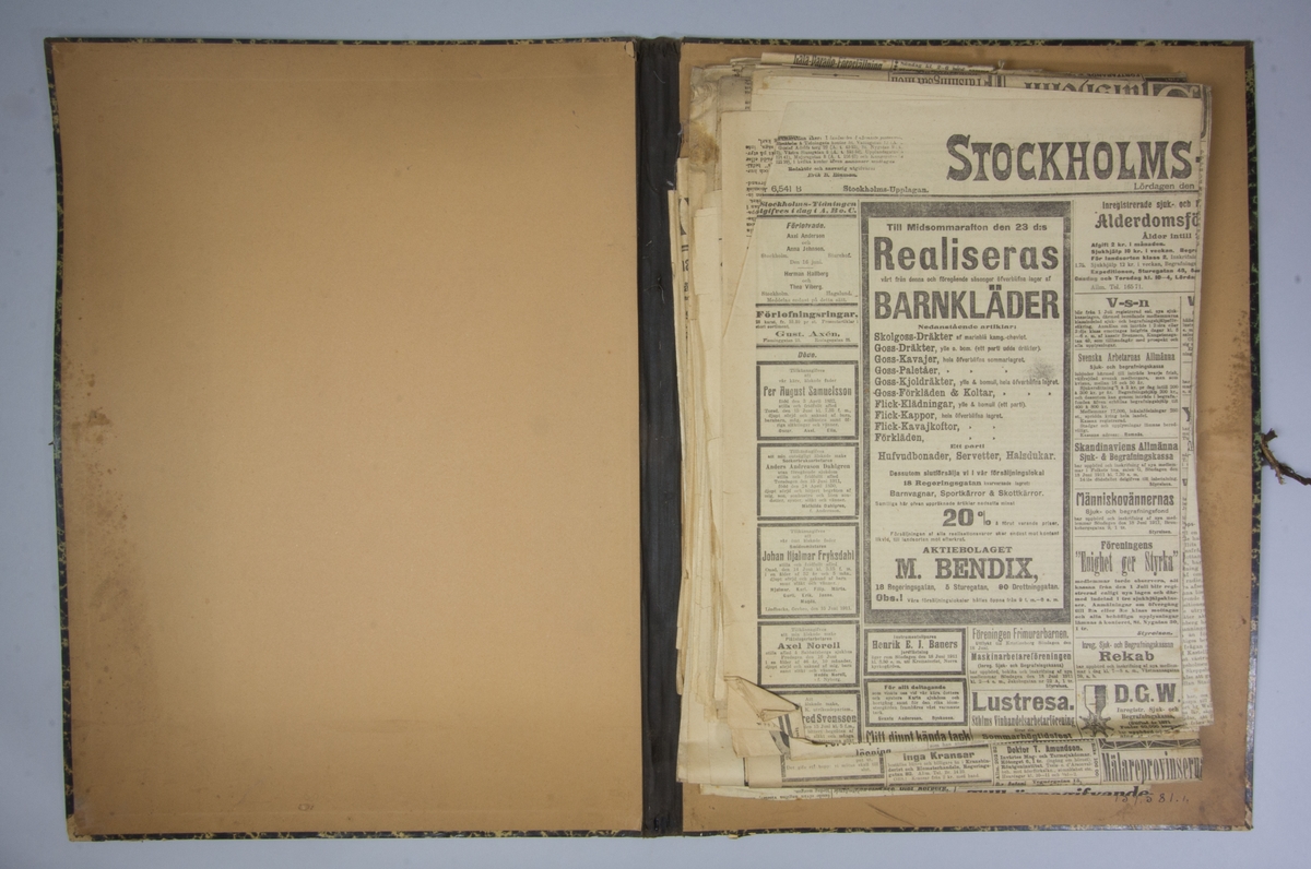 Portfölj av marmorerad papp. Sammanhållen med knytband. Rygg av svart linne. Innehåller enbart flera exemplar av Stockholms Tidningen från 1911.