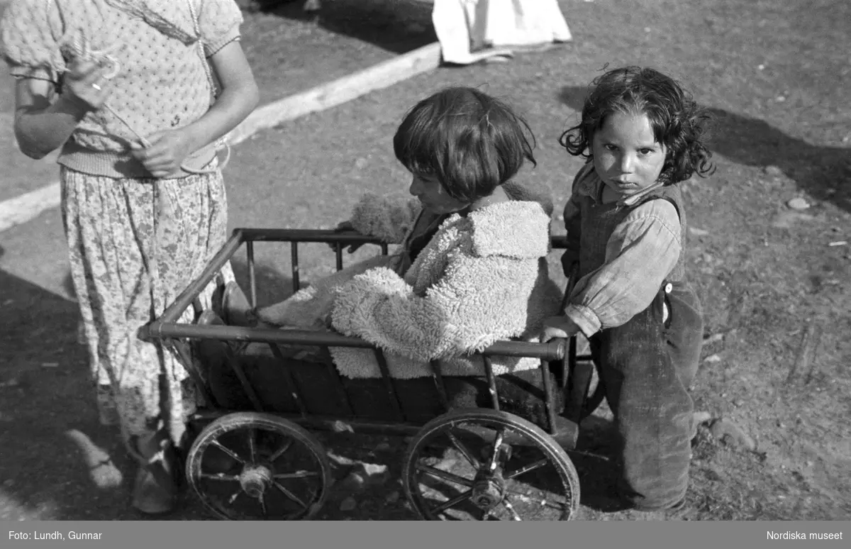 Tre barn leker med en vagn/skrinda. Familjen Taikons läger i Johanneshov, södra Stockholm.