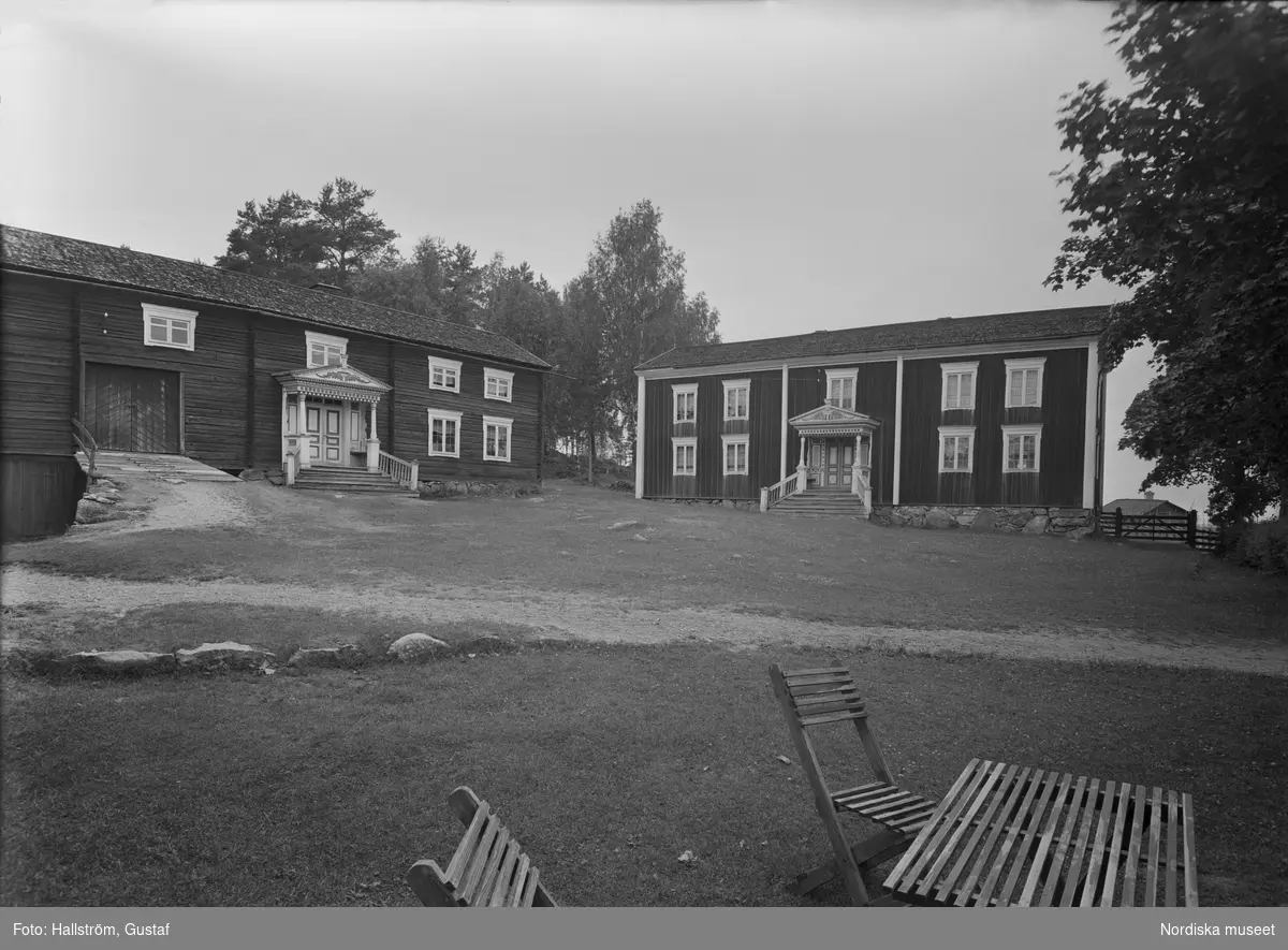 Bångagården (Bångsgården) i Runemo by, Alfta socken, Hälsingland. Gårdsplanen med de båda boningshusen snett framifrån. På gårdsplanen står trädgårdsmöbler.