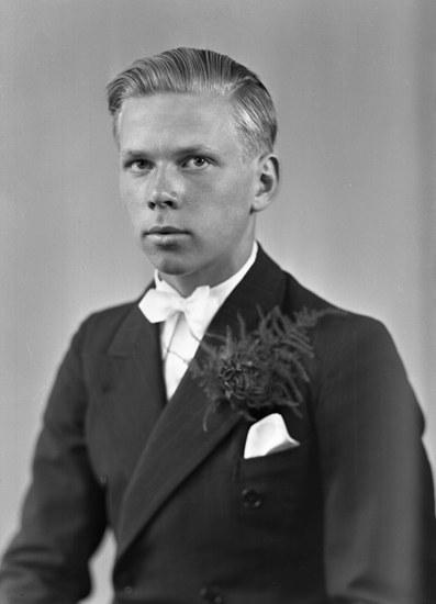 Foto av en okänd ung man i konfirmationskostym med vit fluga. Bröstbild ...